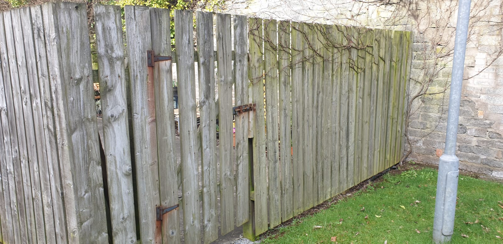 A wooden fence is sitting in the grass next to a pole.
