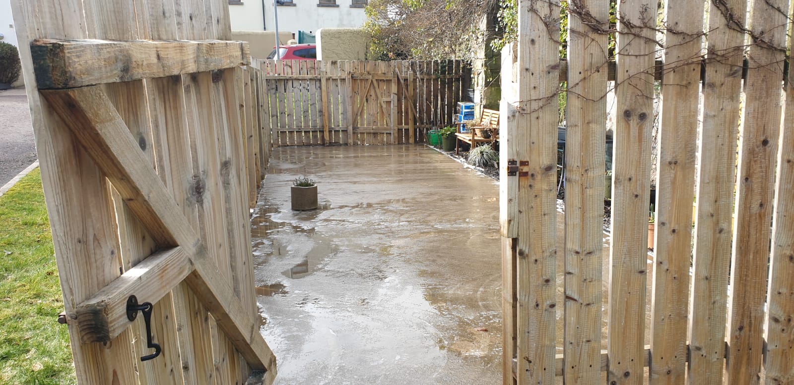 A wooden fence is open to a concrete driveway.