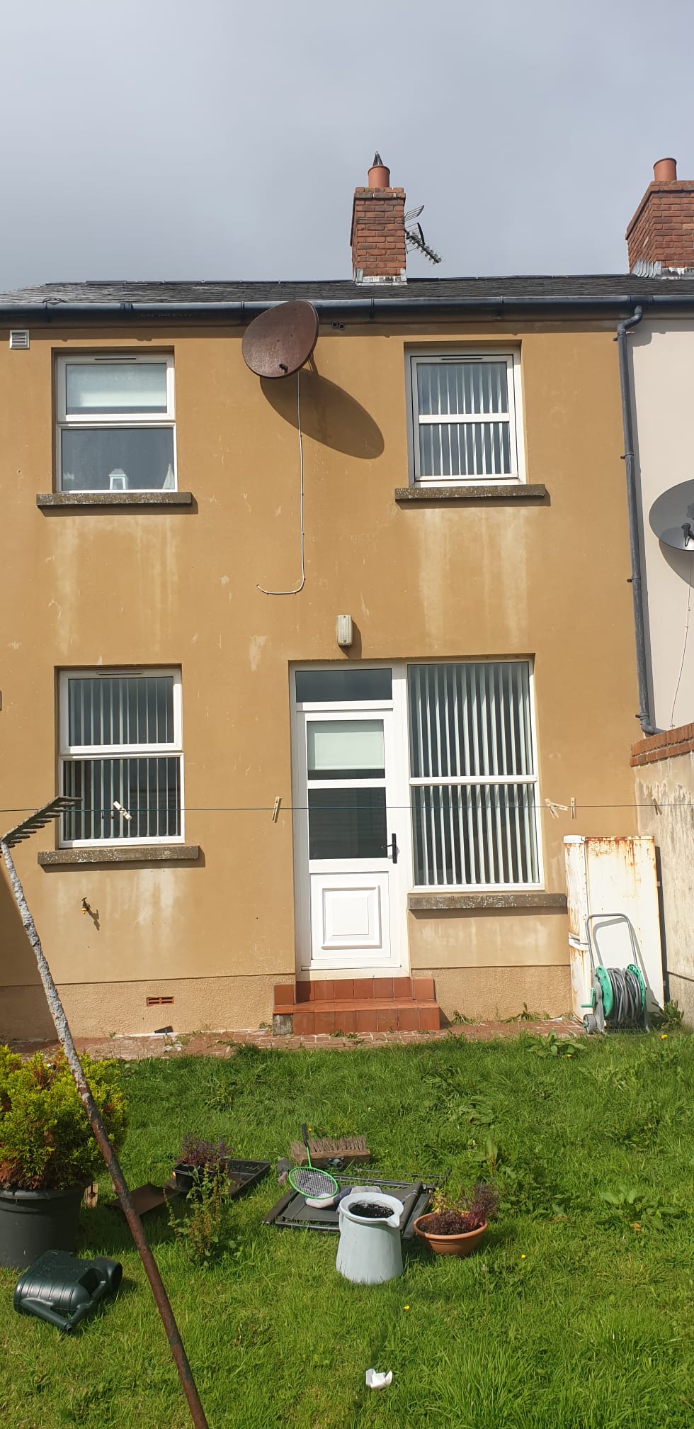 A house with a satellite dish on the roof and a lawn in front of it.