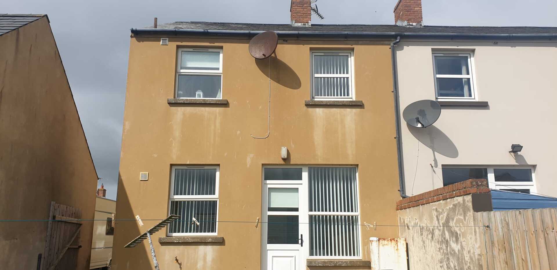 A yellow and white house with a satellite dish on the roof.