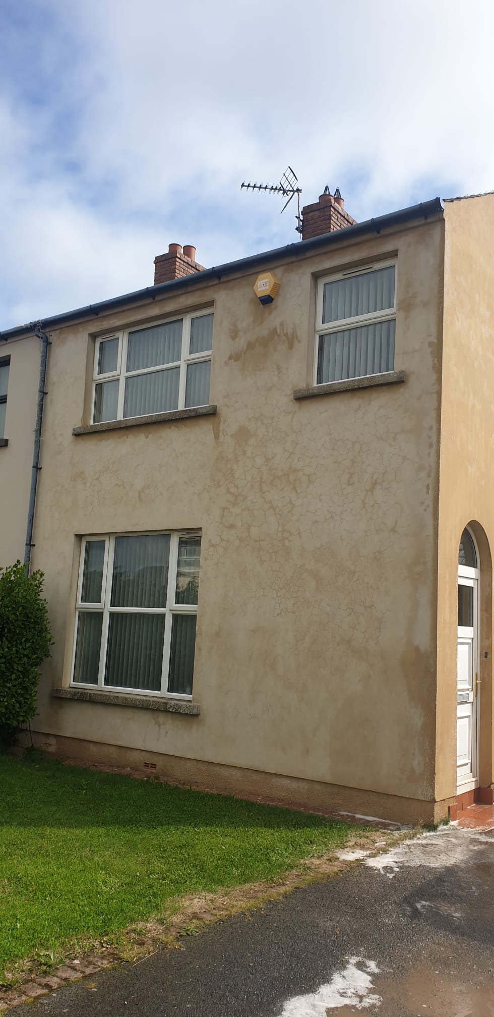 A house with a lot of windows is sitting on top of a lush green field.