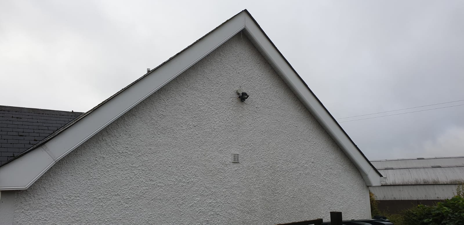 A white house with a roof and a bird on it.