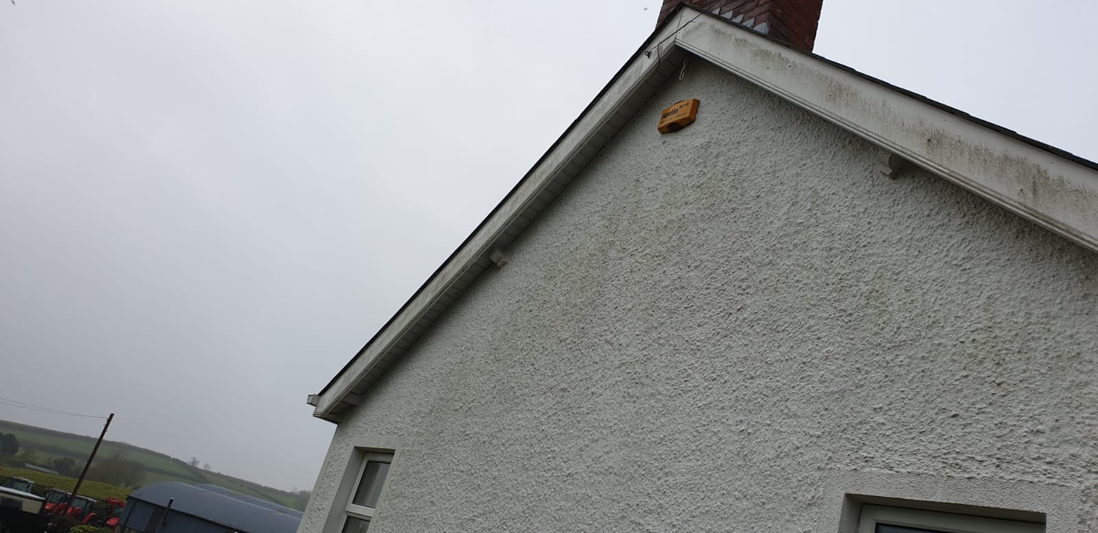 A white house with a chimney on the roof on a cloudy day.