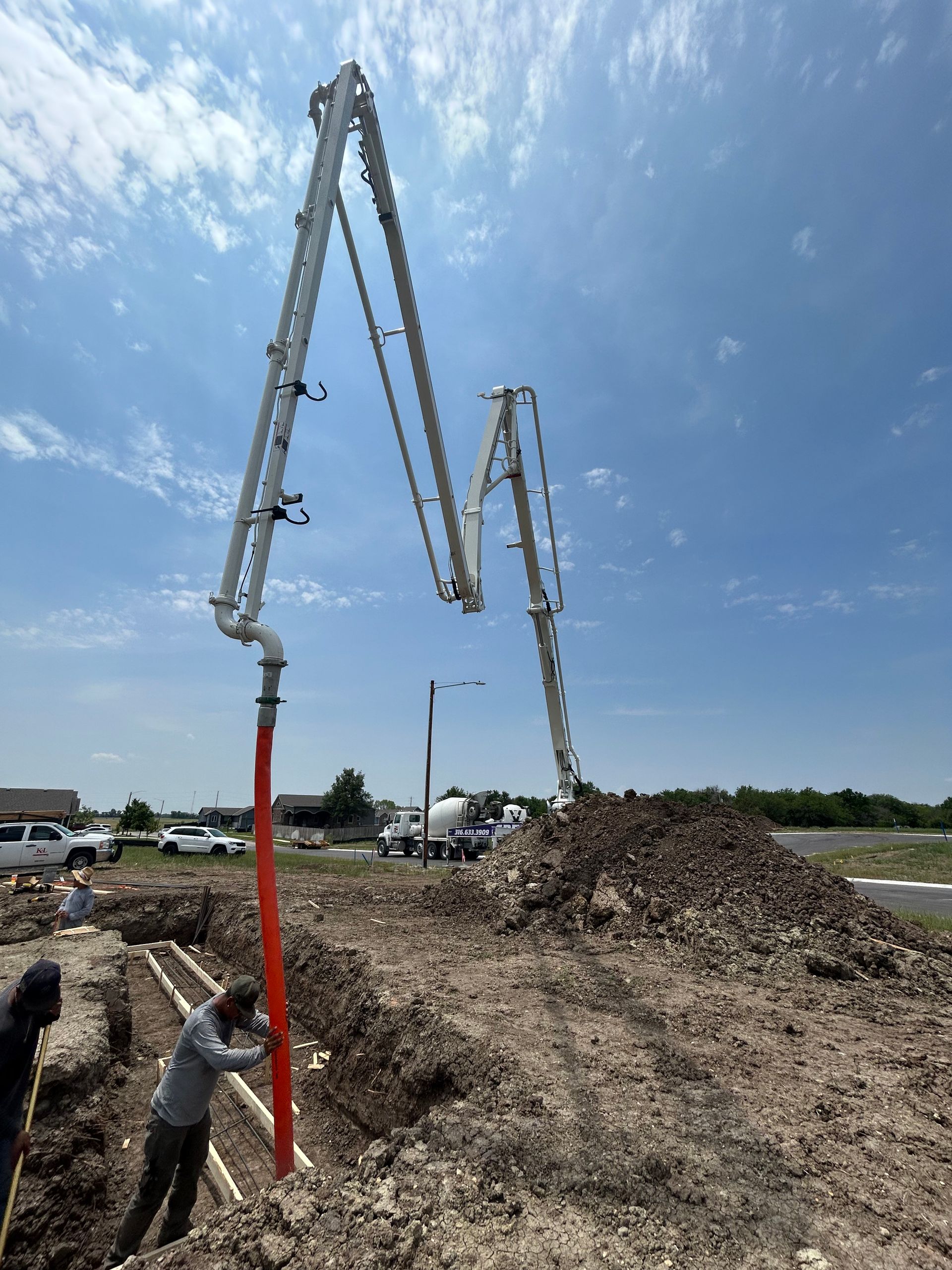 A concrete pump is being used to pump concrete into a pile of dirt.