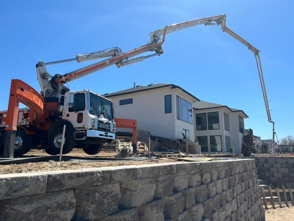 A truck is pumping concrete into a wall in front of a house.