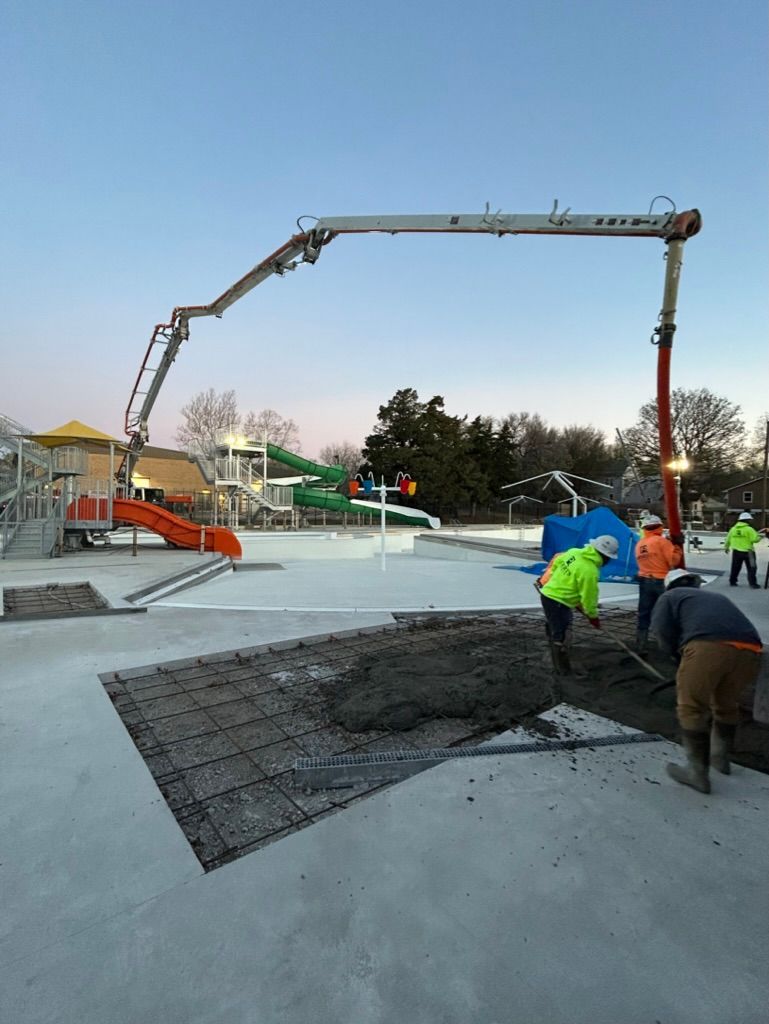 A group of construction workers are working on a concrete skate park.