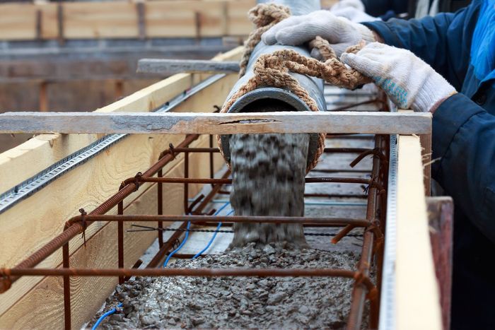 a worker is pouring concrete into a concrete form