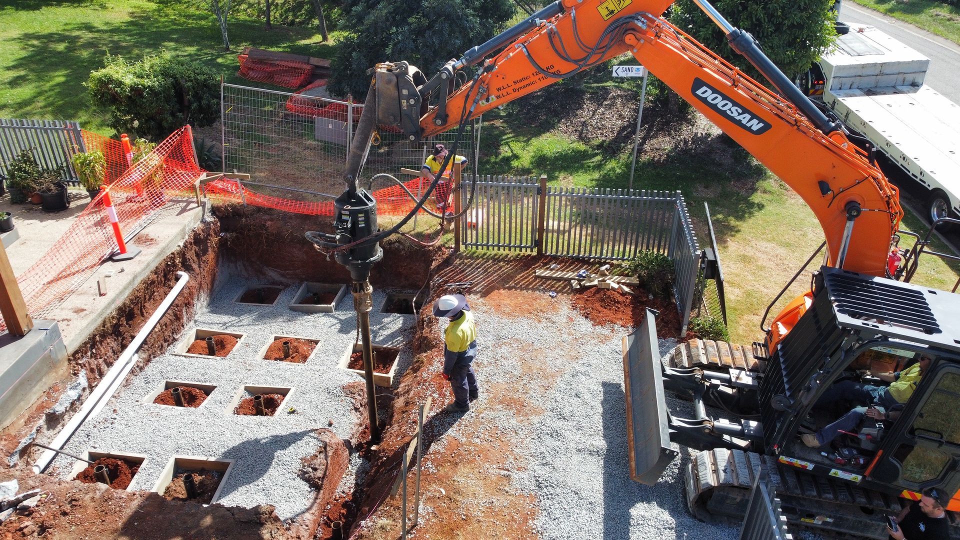 A Large Orange Excavator Is Digging A Hole In The Ground — Southeast QLD — East Coast Group of Companies