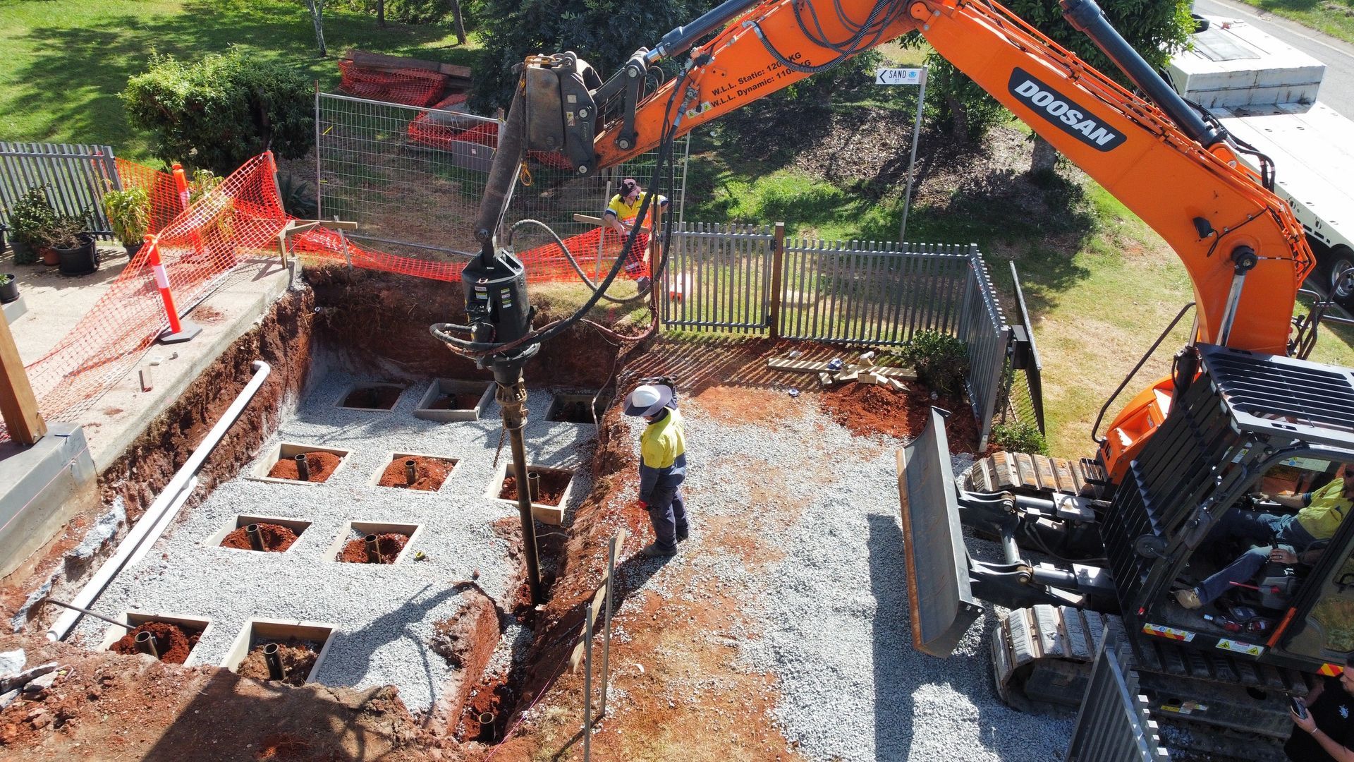A large orange excavator is digging a hole in the ground.