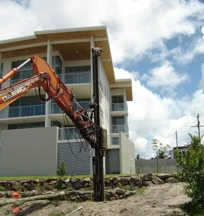 Boring rig installing steel screw piles into the ground for deep foundation support.