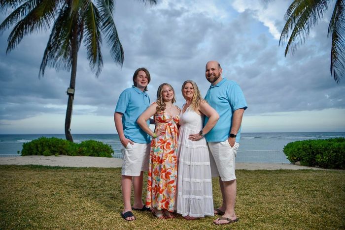 A family is posing for a picture in front of a tree.