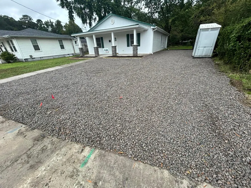 A white house with a gravel driveway in front of it.
