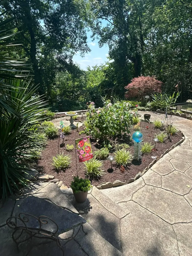 A patio with a table and chairs in the middle of a garden.