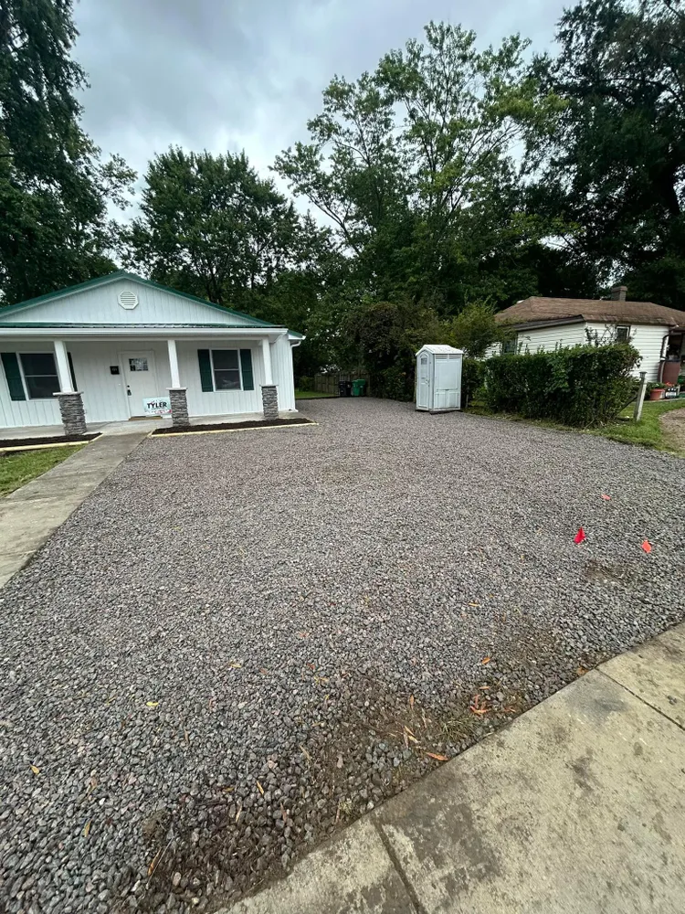 A white house with a gravel driveway in front of it.