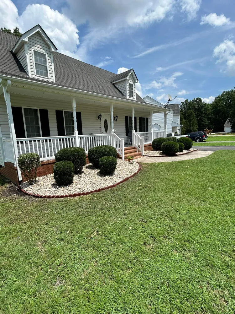 A white house with a large porch and a lush green lawn.