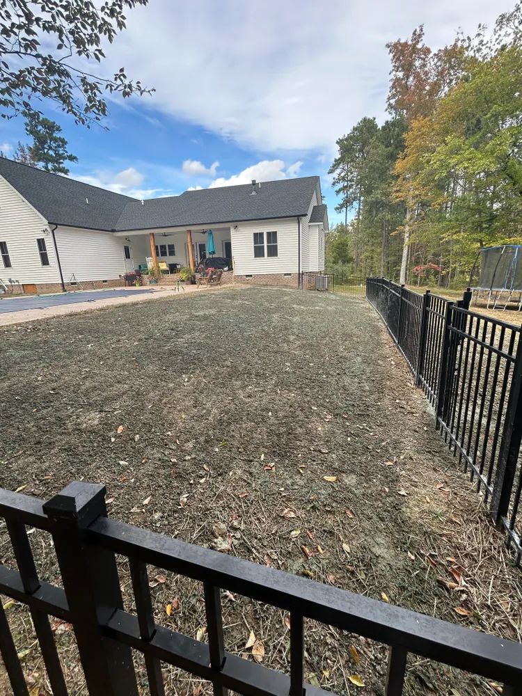 A large yard with a fence and a house in the background.