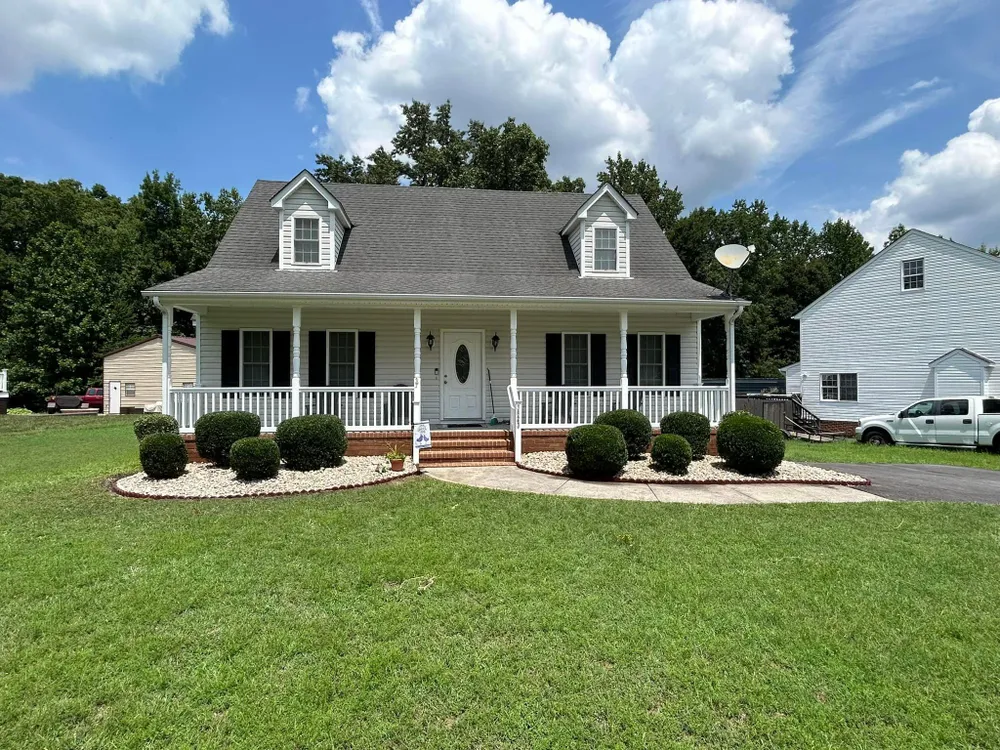 A white house with a porch and a truck parked in front of it.