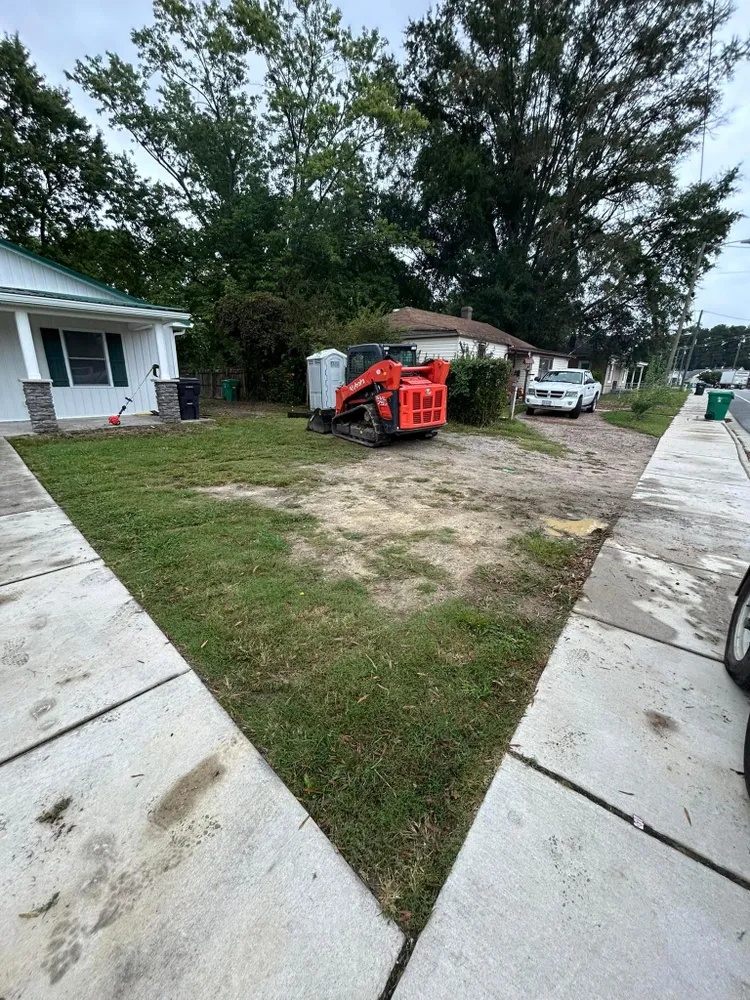 A red tractor is parked in front of a house next to a sidewalk.