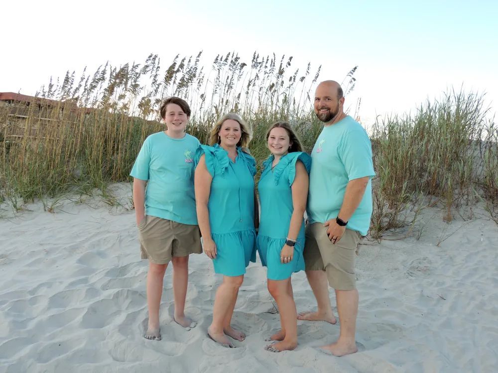 A family is posing for a picture on the beach.