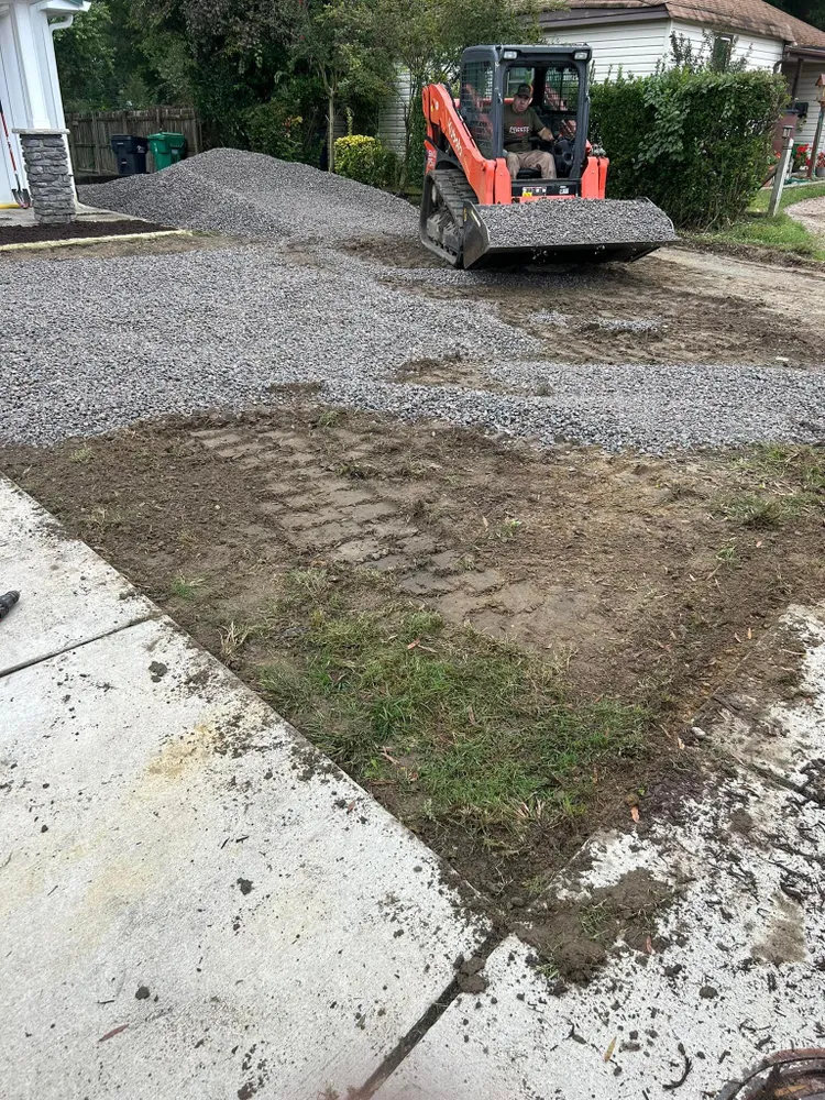 A bulldozer is moving gravel in a driveway.