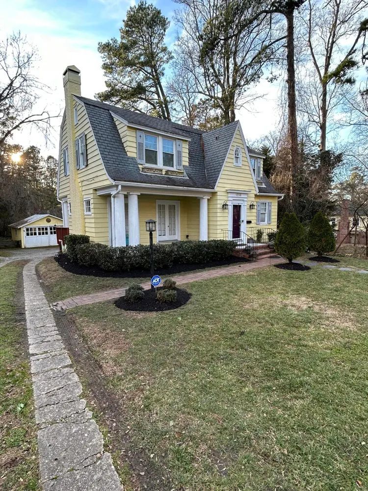 A large yellow house with a gray roof and a walkway leading to it.