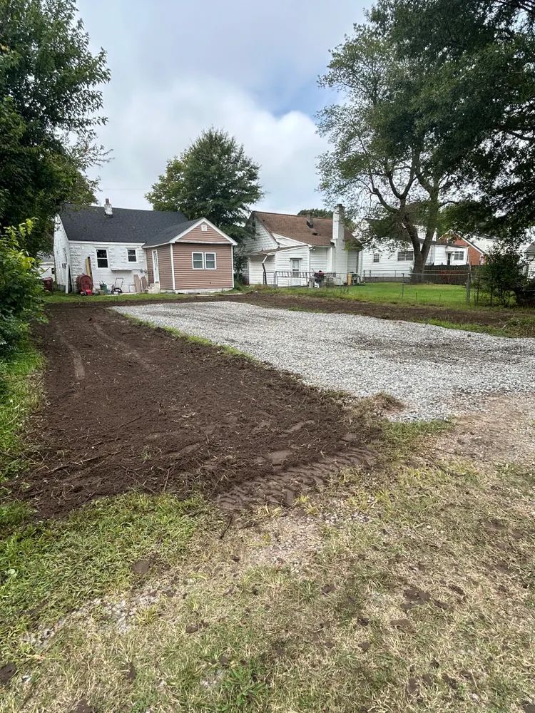 A dirt road leading to a house with trees in the background.