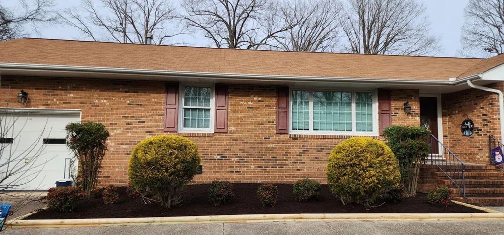 A brick house with a lot of bushes in front of it.