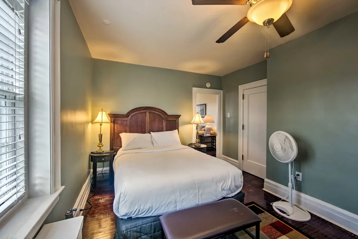 A bedroom with a king size bed and a ceiling fan.