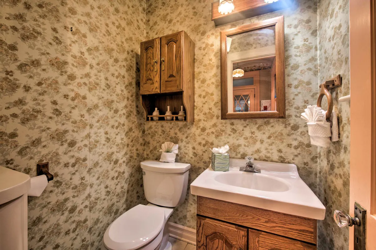 A bathroom with a toilet , sink and mirror.