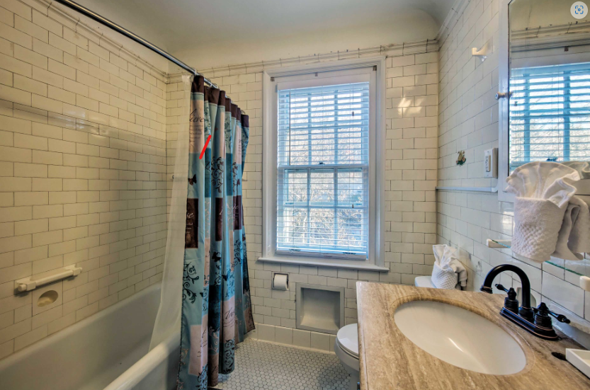 A bathroom with a sink , toilet , tub and window.