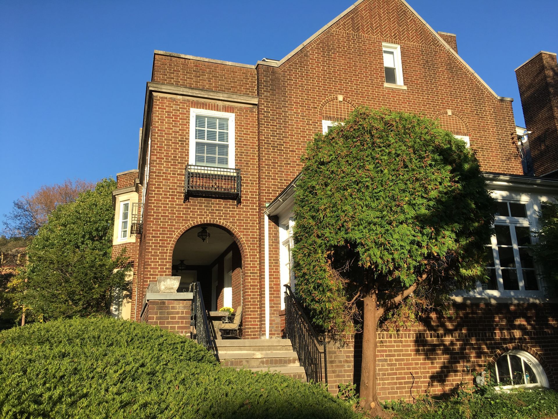 A large brick house with a tree in front of it.