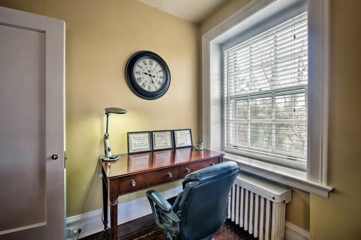 A room with a desk and chair and a clock on the wall.