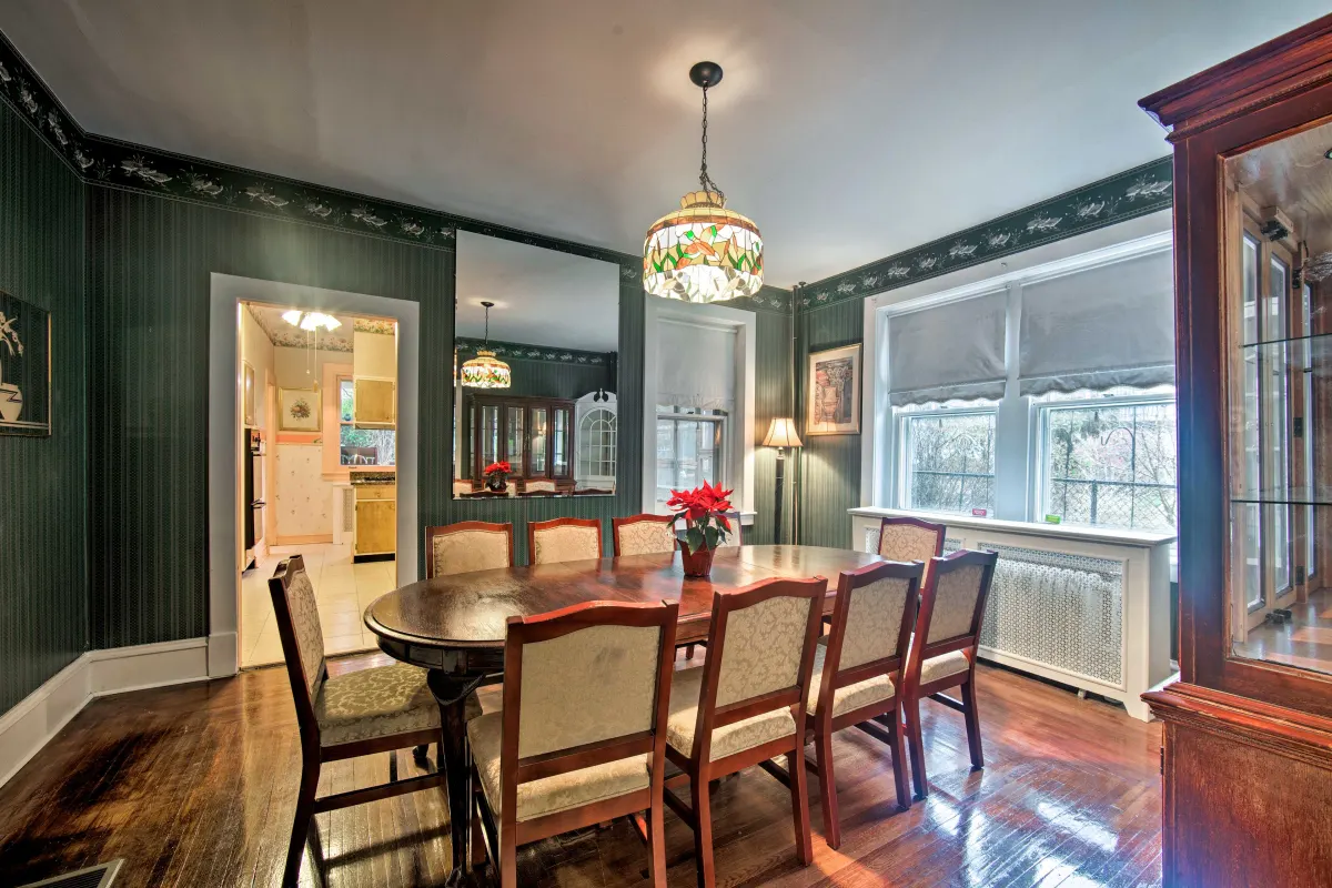 A dining room with a table and chairs and a mirror.