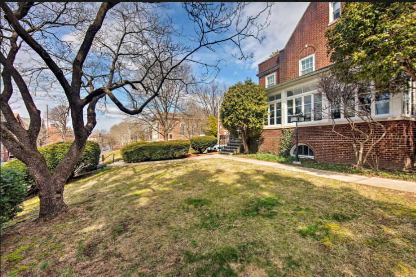 A large brick house with a large lawn in front of it.
