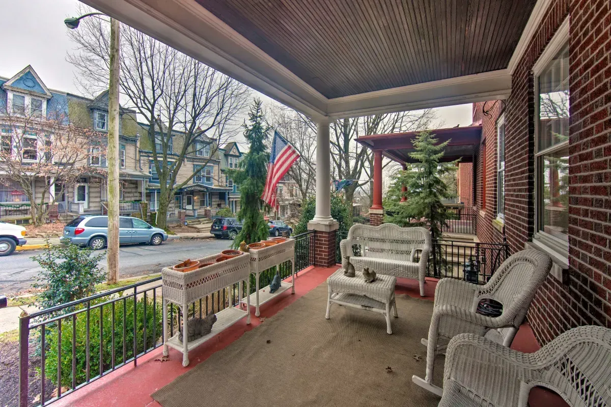 A porch with rocking chairs , a table and a bench.
