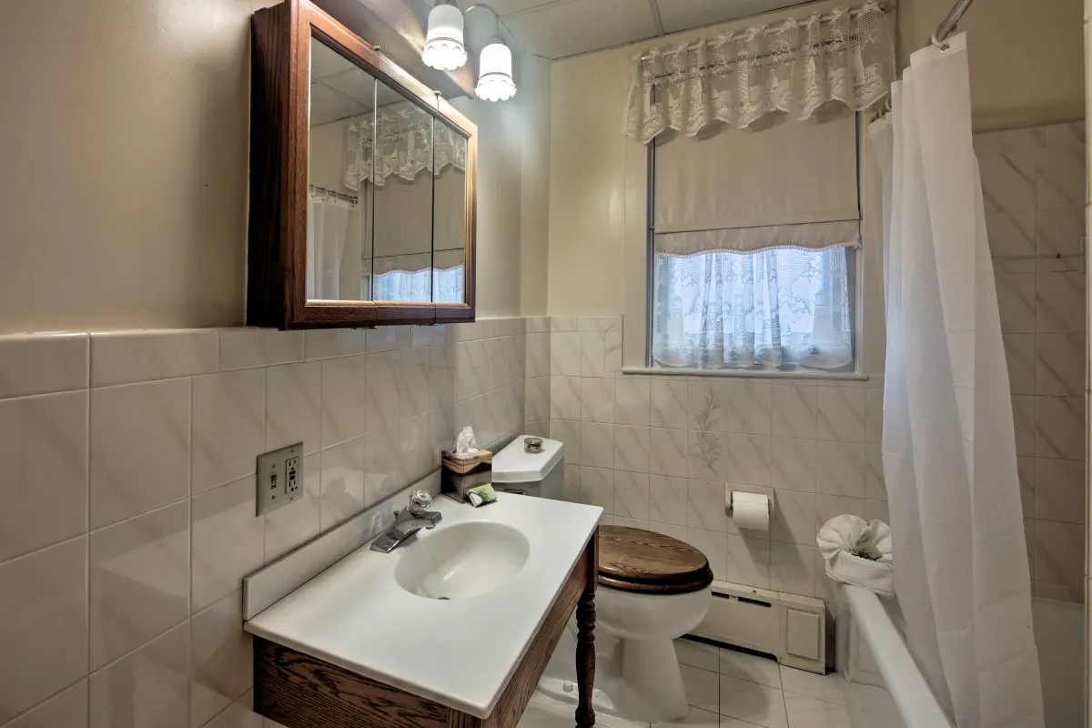 A bathroom with a toilet , sink , mirror and shower curtain.