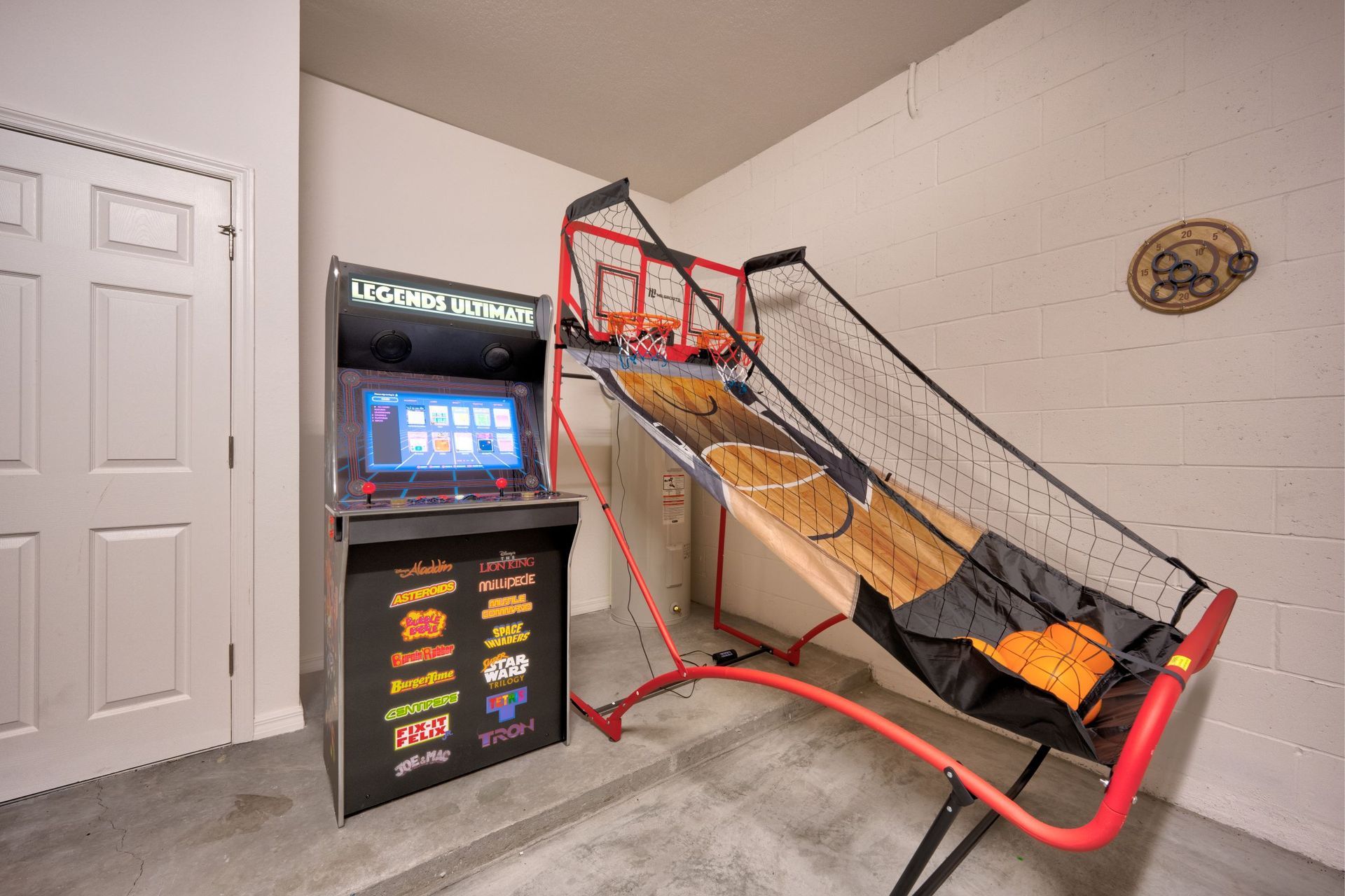 A room with a basketball hoop and an arcade machine.
