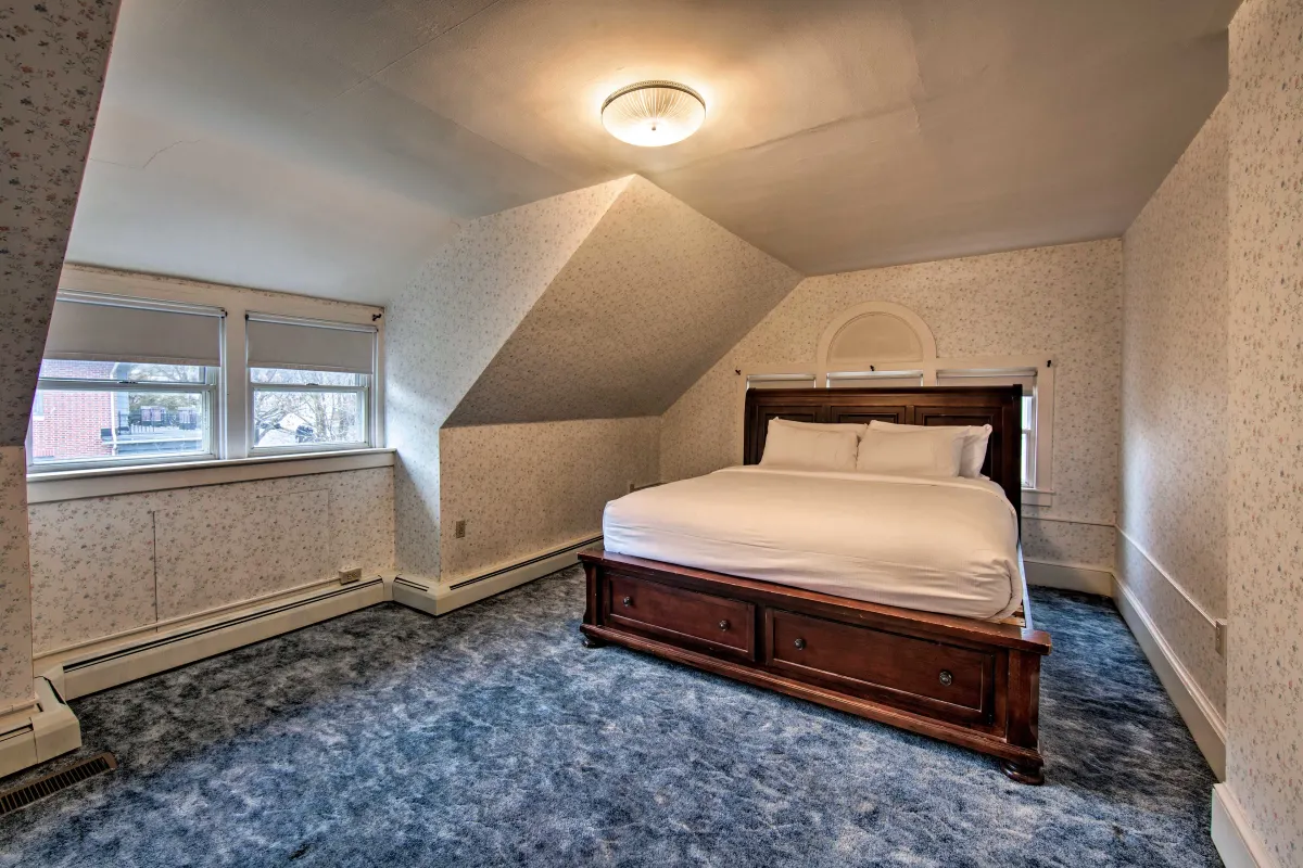 A bedroom with a king size bed and a blue carpet.