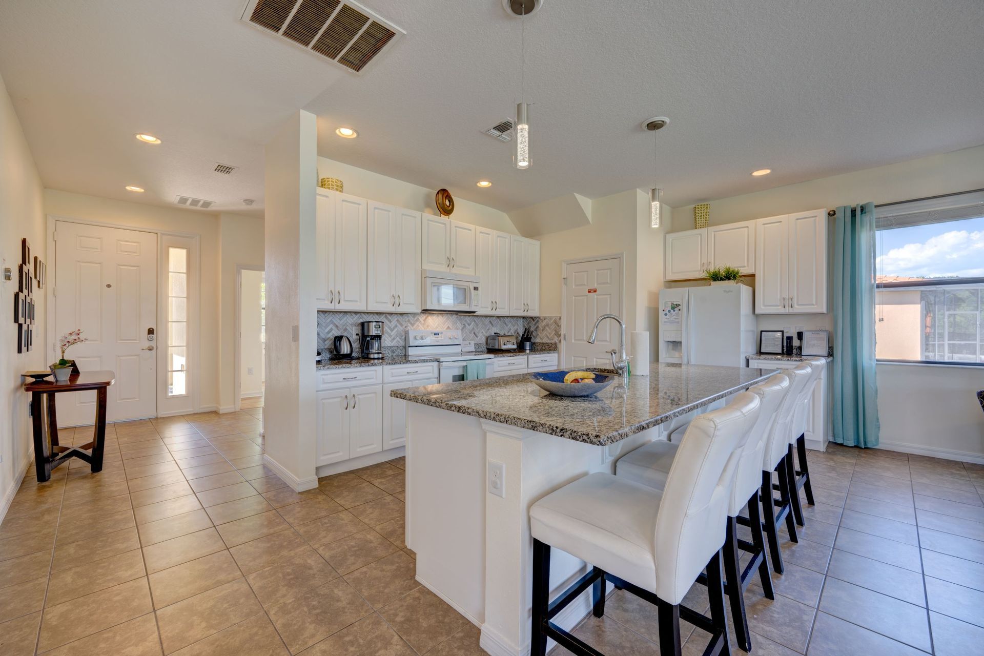 A kitchen with white cabinets , granite counter tops , and a large island.
