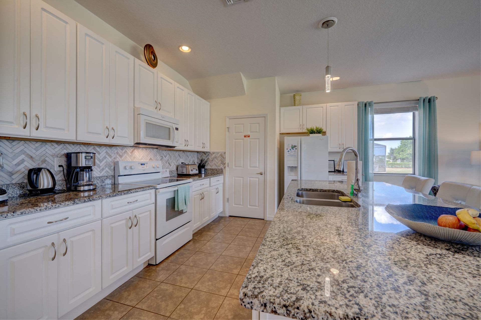 A kitchen with white cabinets and granite counter tops.