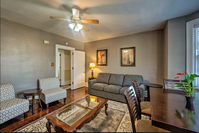 A living room with a couch , chairs , a table and a ceiling fan.