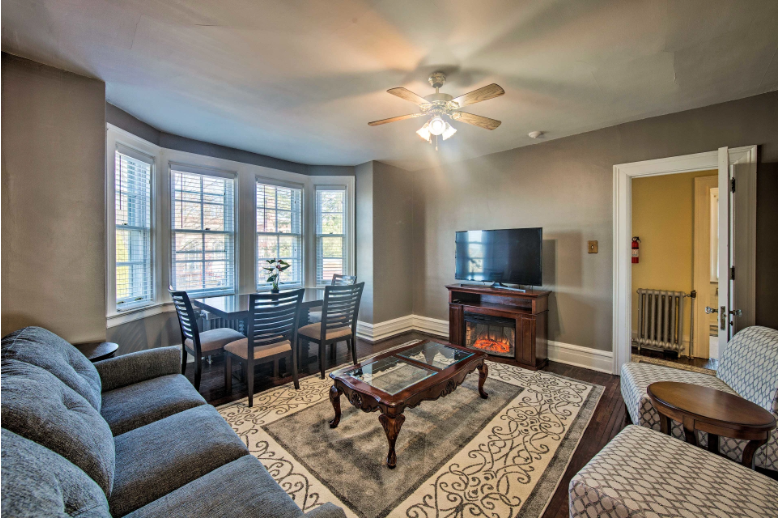 A living room with a couch , chairs , table , fireplace and television.