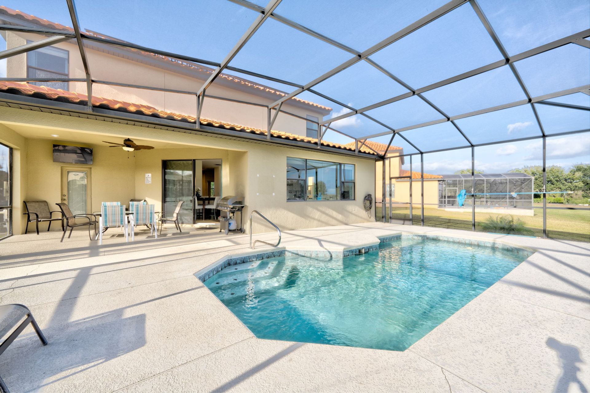 A large swimming pool in front of a house with a screened in area