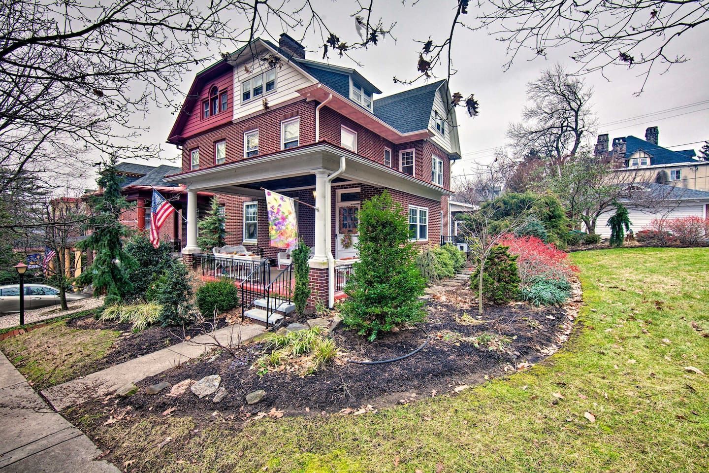 A large brick house with a porch and a large lawn in front of it.