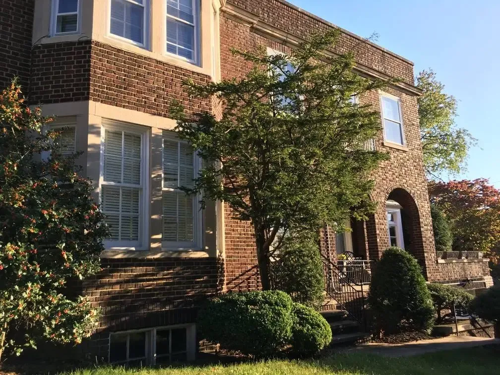 A large brick building with a lot of windows and trees in front of it