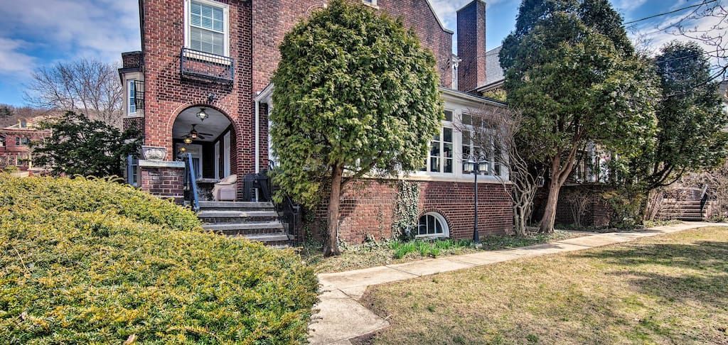 A large brick house with a path leading to it and trees in front of it.