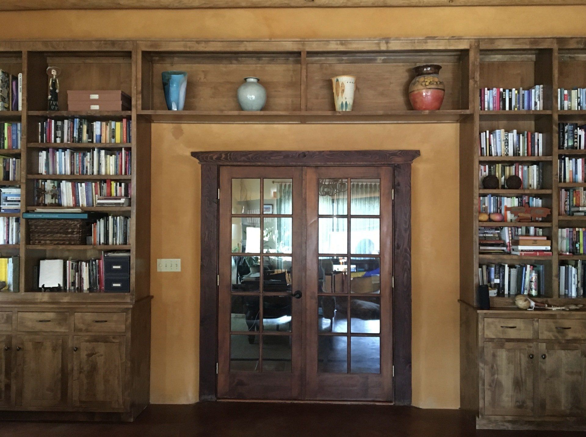 Interior glass door with towering wooden bookshelves filled with books on either side