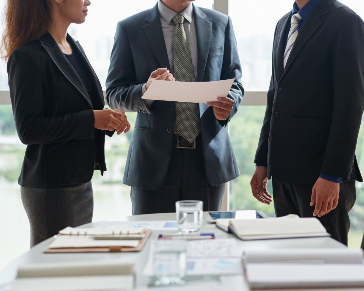 Three people reviewing documents at a table in an office. Trifecta: Charged with Domestic Assault, Order of Protection and Facing Divorce in Nashville, Tennessee