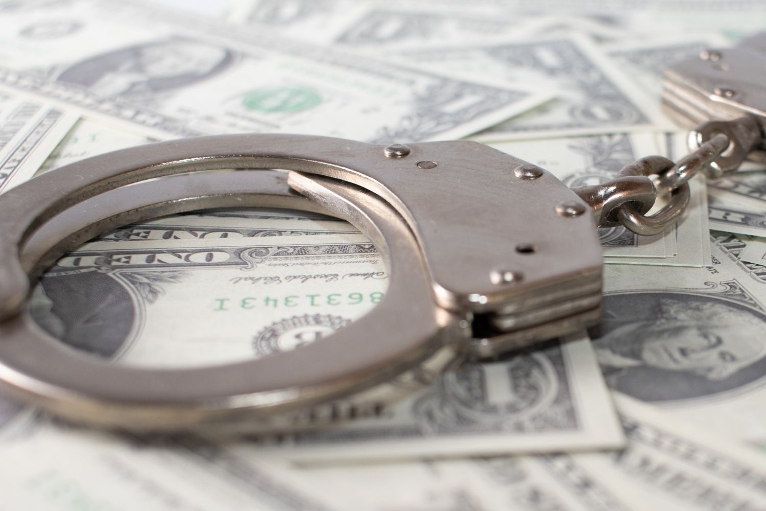Handcuffs on top of a pile of US dollar bills. White Collar Crimes in Nashville, Tennessee