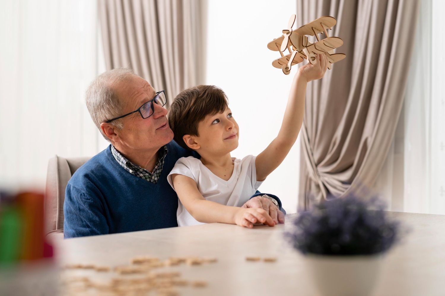 Grandfather and child play with a wooden airplane, sitting at a table in a bright room. Grandparent’s Rights in Nashville, Tennessee